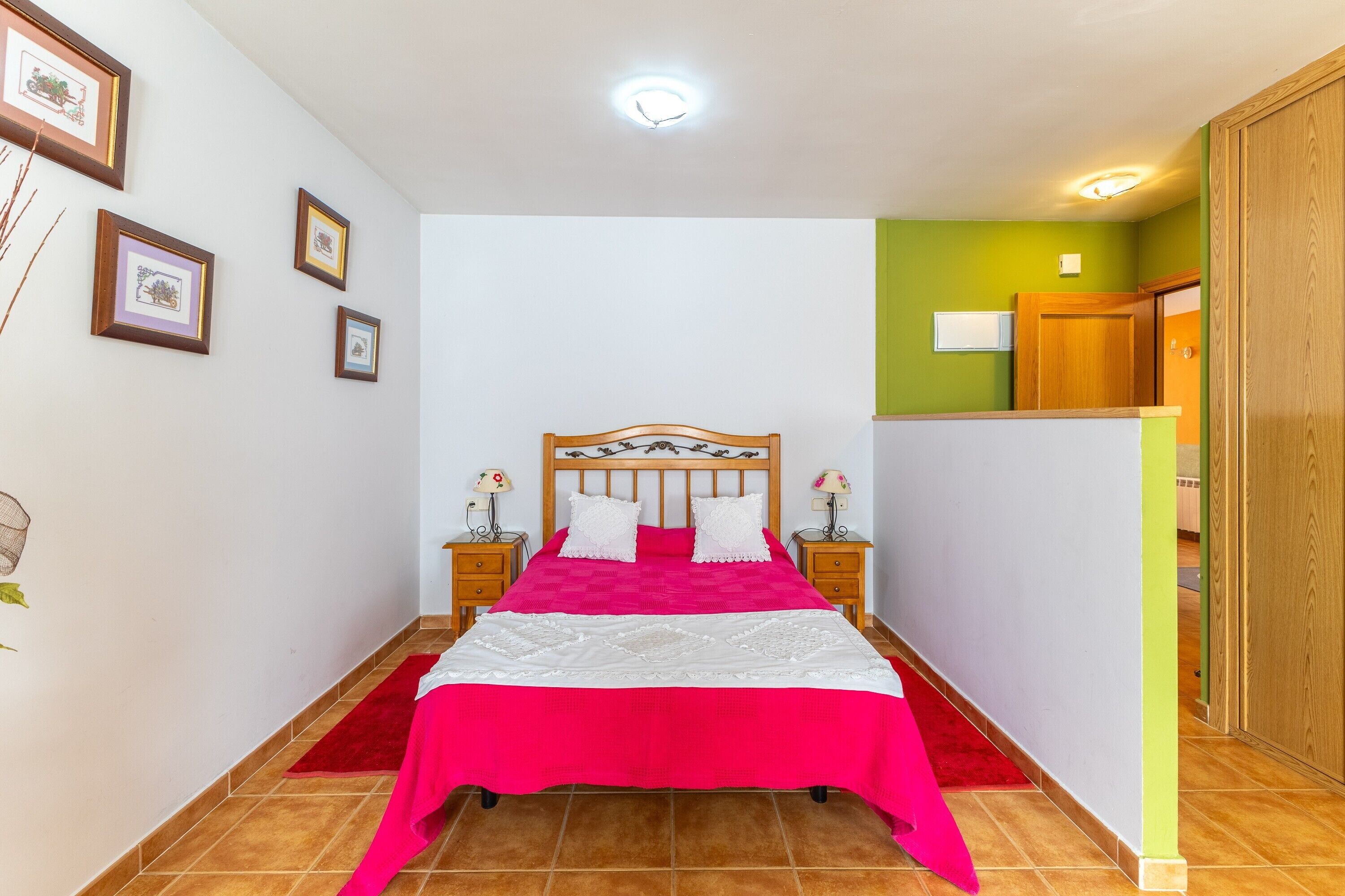 Een slaapkamer met een bed, nachtkastjes, ingelijste foto's en een garderobe.