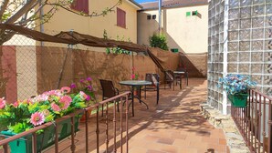 A courtyard with outdoor seating, a stone staircase, and potted plants.