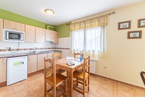 A compact kitchen with a microwave, sink, and a dining table with chairs.