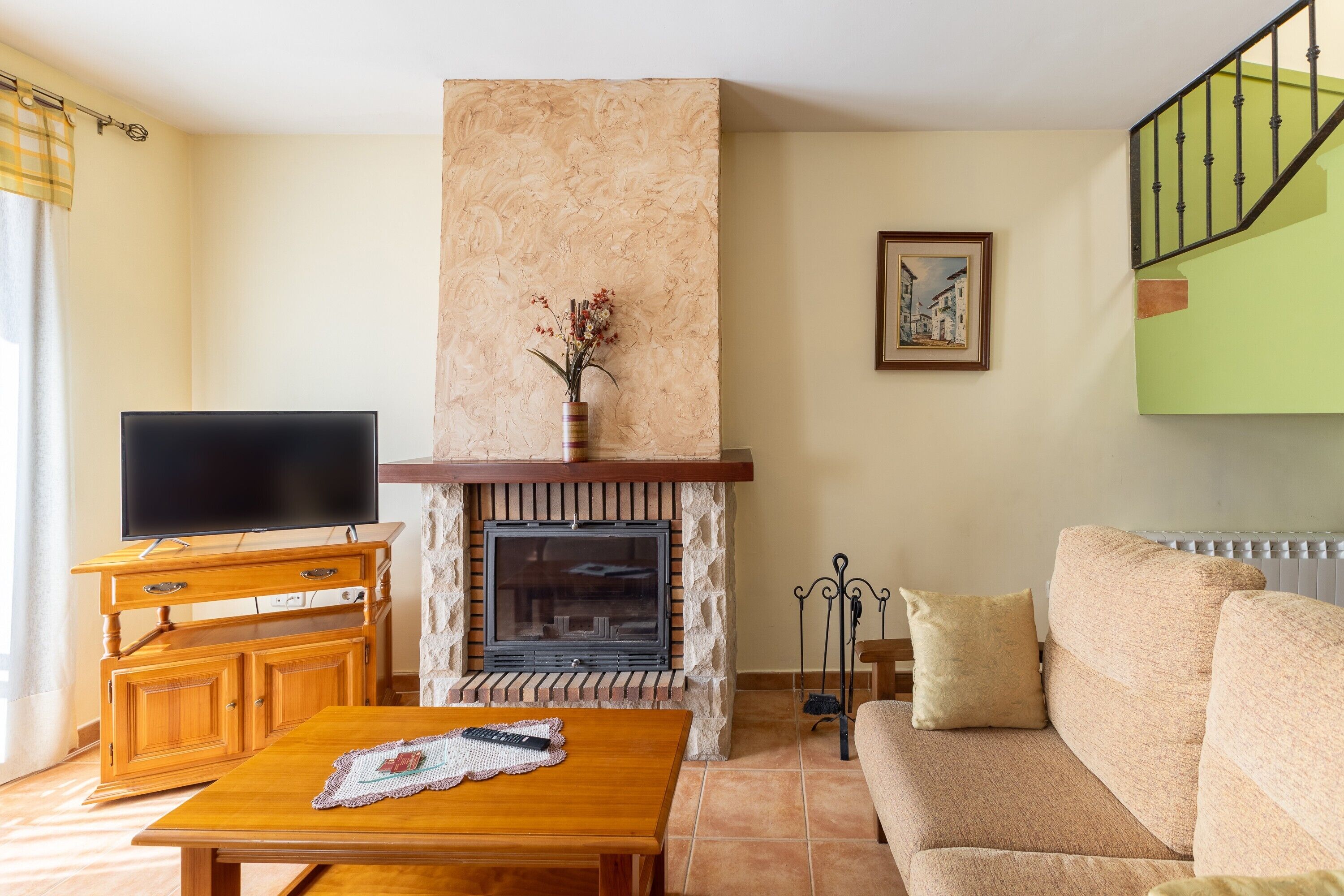 Una sala de estar con chimenea, un sofá, un televisor y una mesa de centro de madera.