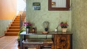 A reception desk with a sign recommending Toprural, a staircase, and a window with a curtain.