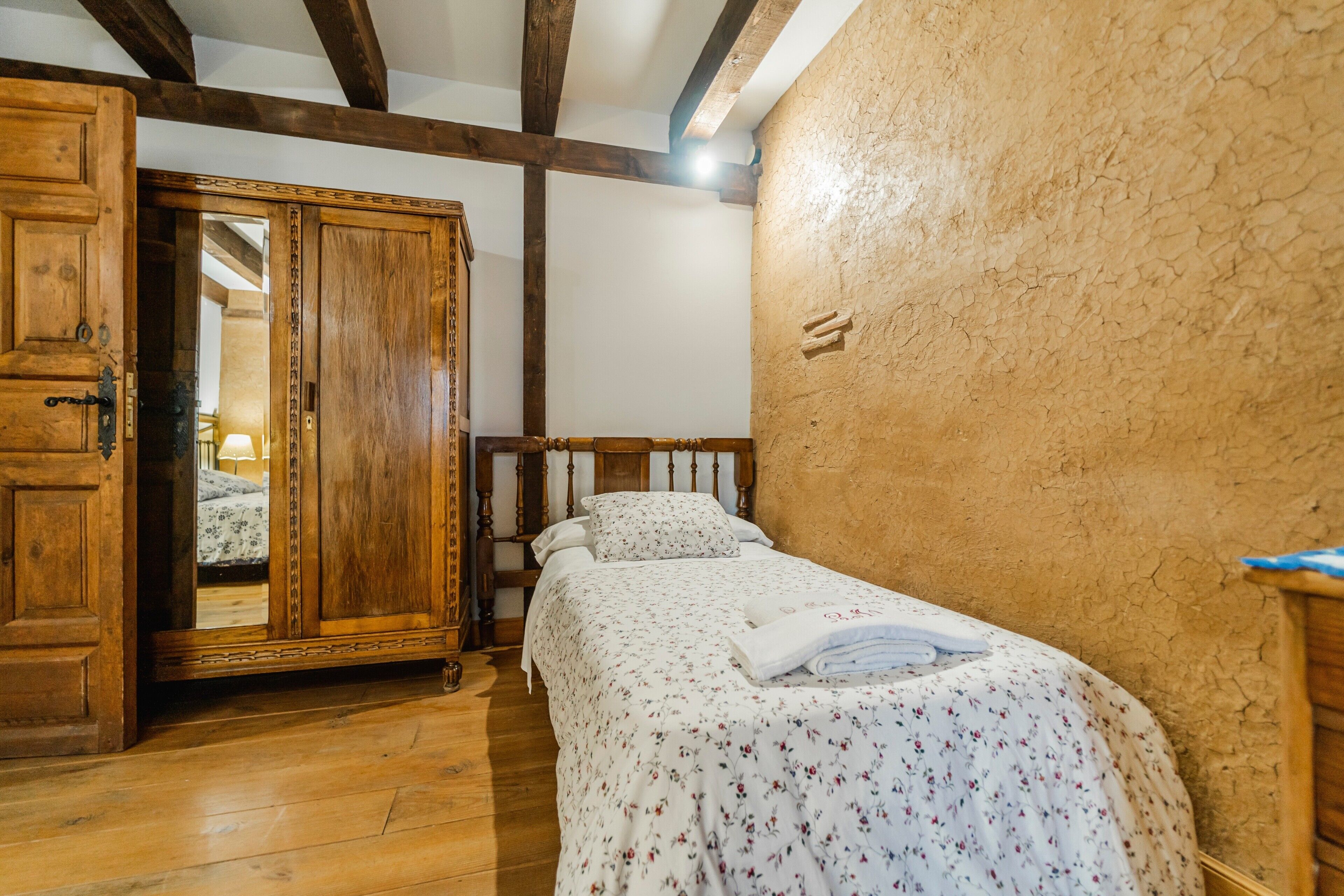 Une chambre avec un lit en bois, une armoire et un miroir.