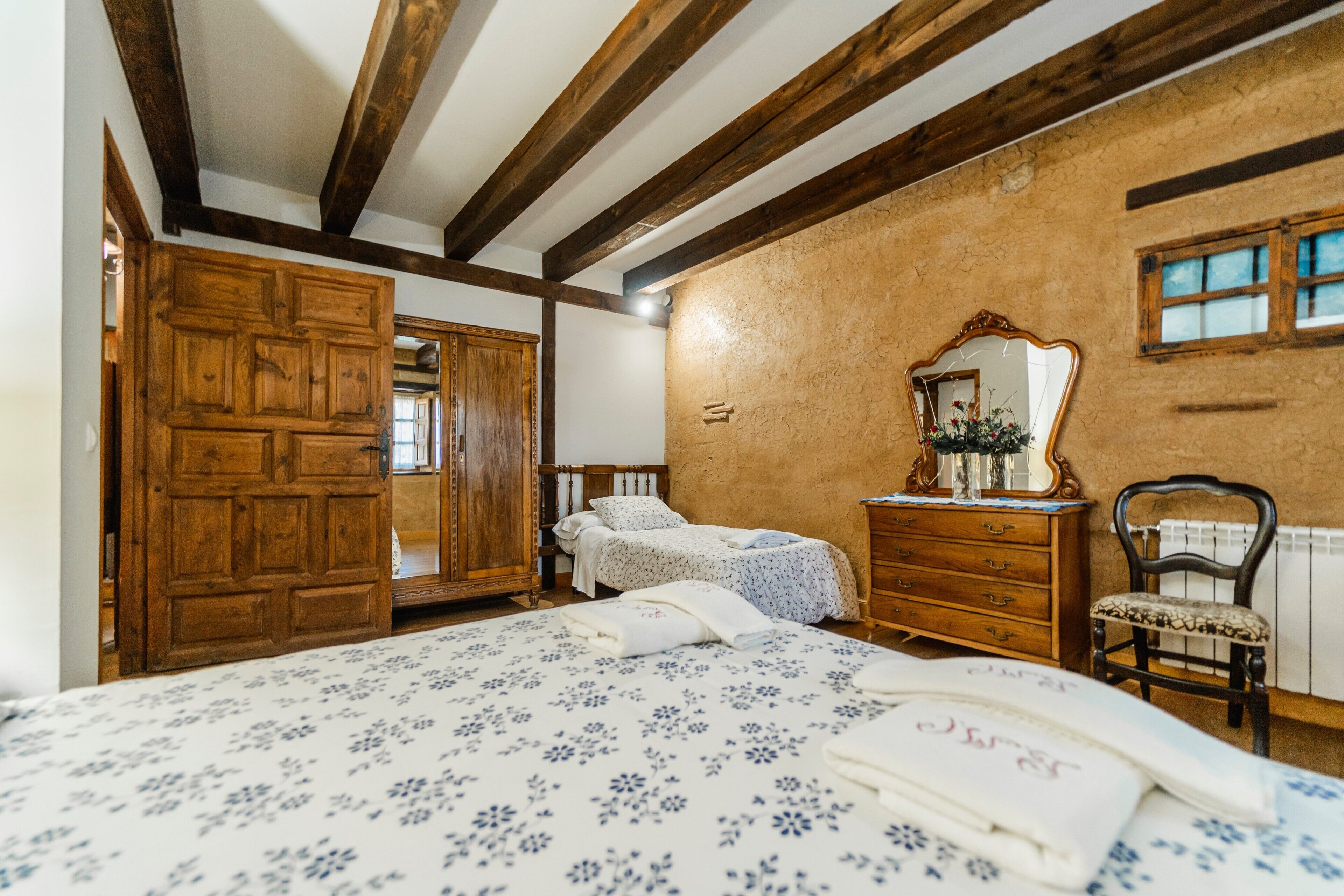 Une chambre à coucher avec un lit en bois, une commode, une chaise et un miroir au mur.