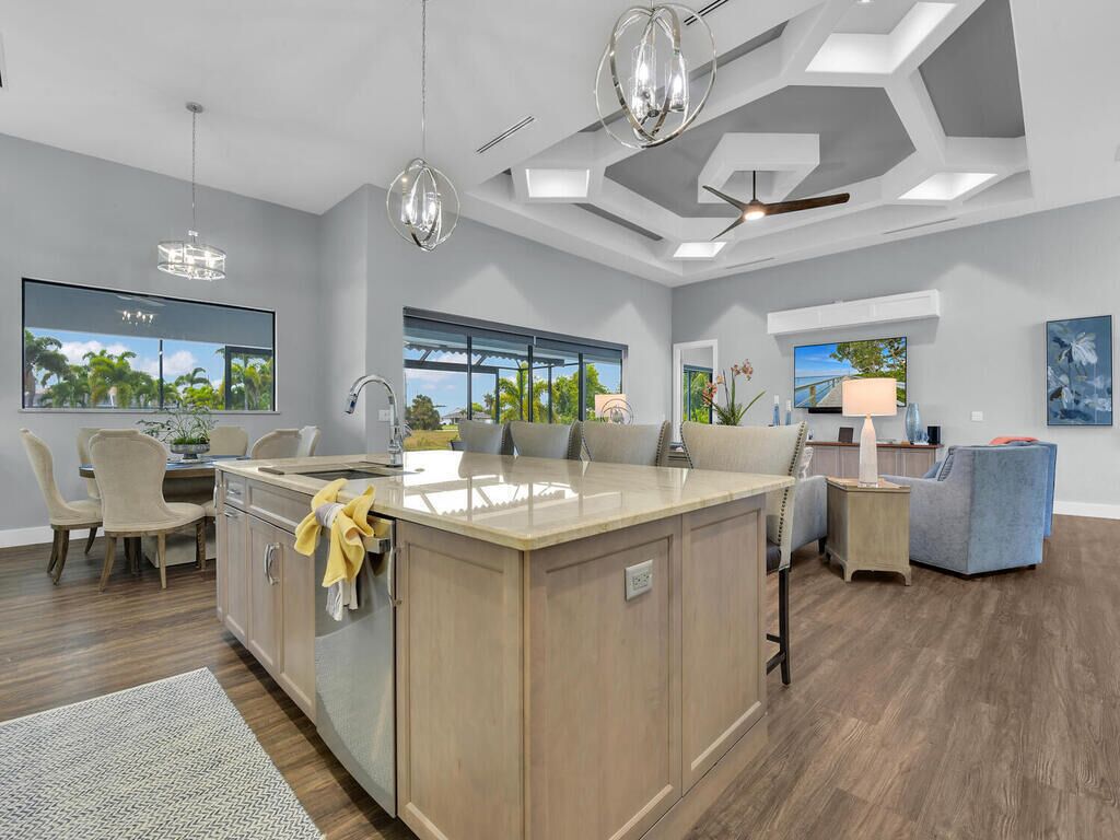 A modern kitchen with a central island, large windows, and a ceiling fan.