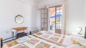 Une chambre avec deux lits, un bureau, un miroir et une fenêtre avec des rideaux.