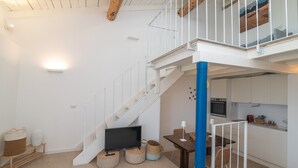 Una escalera que conduce a un segundo piso, un comedor con mesa y sillas, y una cocina con armarios y electrodomésticos.