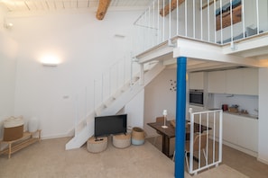 Un escalier menant à un deuxième étage, un coin repas avec une table et des chaises, et une cuisine équipée de placards et d’appareils électroménagers.
