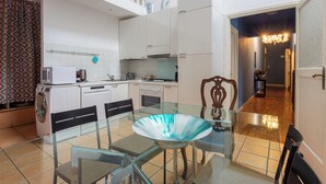 Una cocina moderna con armarios blancos, una mesa de comedor de cristal y una lavadora.