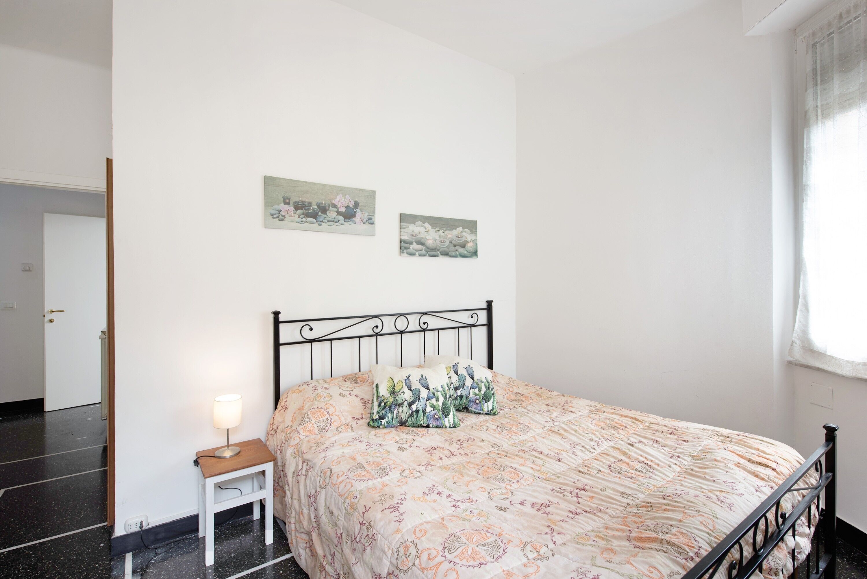Ein Schlafzimmer mit einem Bett, einem Nachttisch, einer Lampe und zwei Bildern an der Wand.