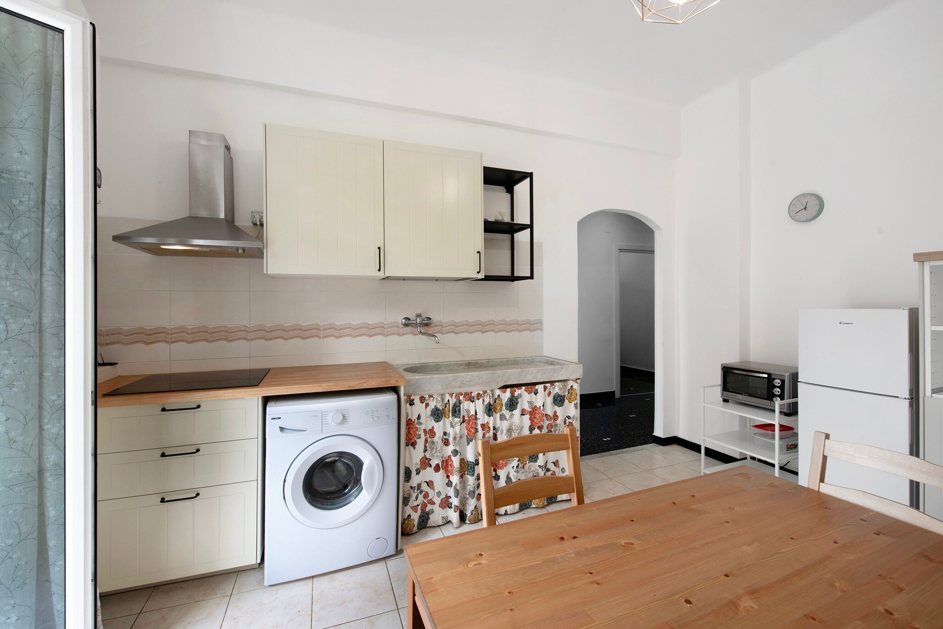 A compact kitchen with a washing machine, a wooden dining table, and a microwave.