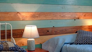 Une chambre à coucher avec une tête de lit en bois, une table de chevet avec une lampe et une couvre-lit matelassé.