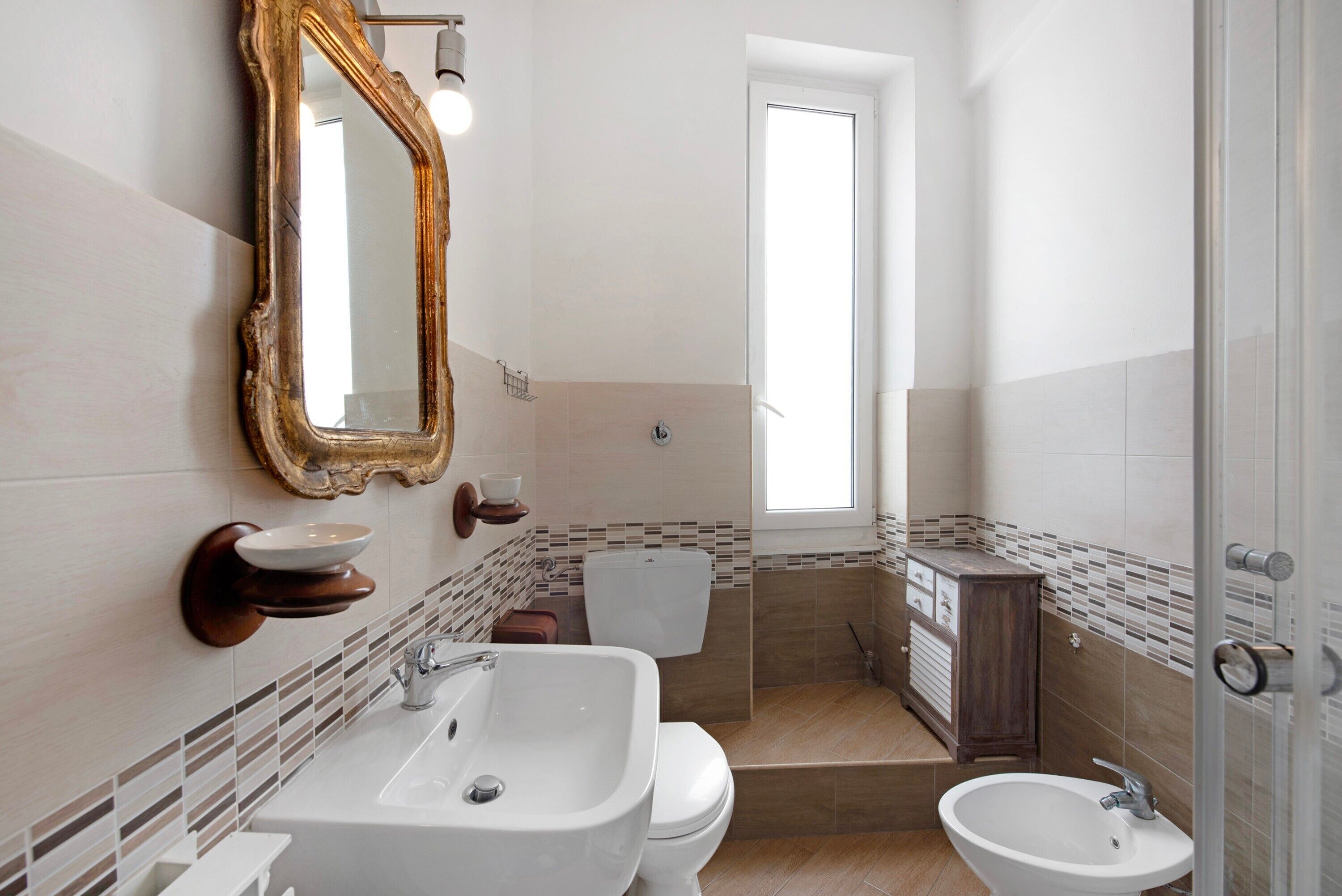 A bathroom with a large mirror, two sinks, a toilet, and a shower area.