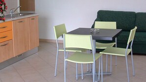 Une petite cuisine moderne avec une table et des chaises, un canapé vert et un tableau encadré au mur.