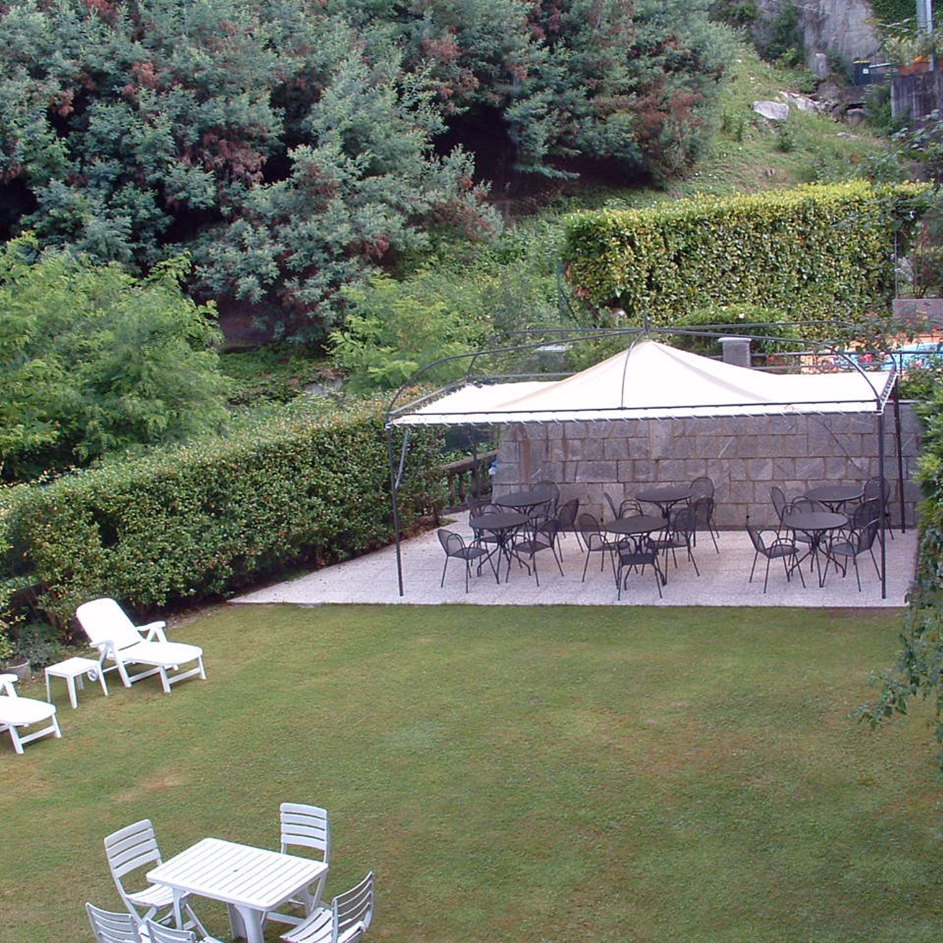 A covered outdoor patio with stone walls and metal tables and chairs.