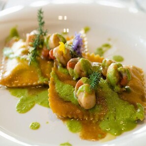 A plate of ravioli with green sauce and garnishes. - Bungalow Pino Nero Bilocale 4 pax (San Michele al Tagliamento)