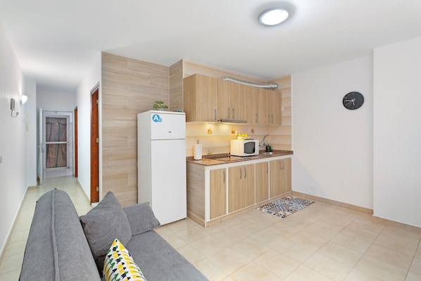 A modern kitchen with wooden cabinets, a refrigerator, and a microwave.