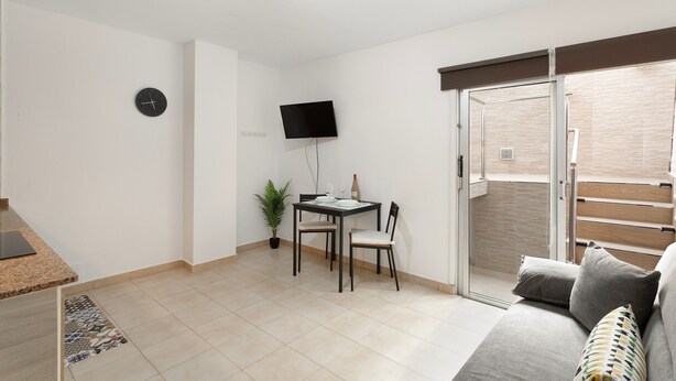 A modern living room with a sofa, a dining table with chairs, a flat-screen TV mounted on the wall, and a sliding glass door leading to a balcony. - Vacation Apartment 'Danoe 3' with Wi-Fi (Mogán)