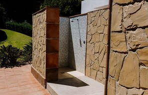 A stone-walled outdoor shower area with a tiled shower enclosure.