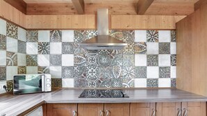 A kitchen with wooden cabinets, a stainless steel range hood, and patterned tile backsplash. - Holiday Home 'Casa El Mirlo' with Private Pool, Wi-Fi and Air Conditioning (Conil de la Frontera)