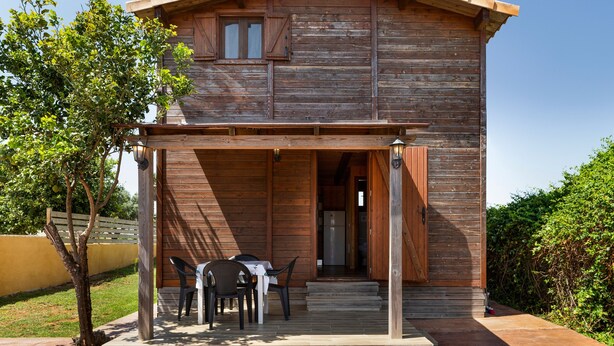 A wooden cabin with a covered patio, a table with chairs, and a door leading inside. - Holiday Home 'Casa El Mirlo' with Private Pool, Wi-Fi and Air Conditioning (Conil de la Frontera)