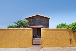 A wooden cabin with a red roof, a yellow exterior wall, and a small porch. - Holiday Home 'Casa El Mirlo' with Private Pool, Wi-Fi and Air Conditioning (Conil de la Frontera)