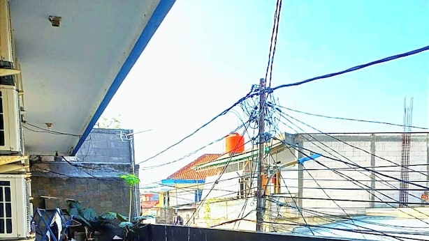 A rooftop terrace with a tiled floor, a black wall, and visible electrical wires. - Kost Griya Marina by Ecommerceloka (Jakarta)