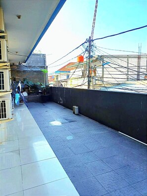 A rooftop terrace with a tiled floor, a black wall, and visible electrical wires. - Kost Griya Marina by Ecommerceloka (Jakarta)