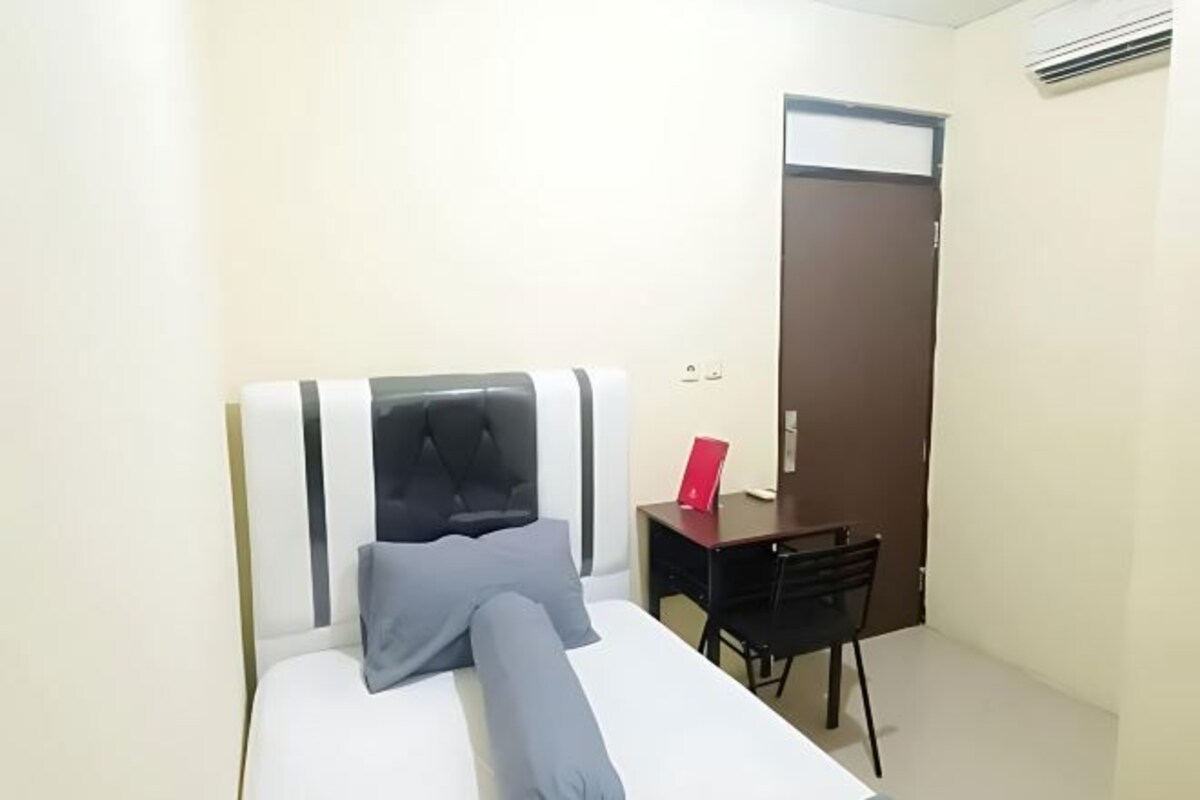 Una habitación pequeña y ordenada con cama, escritorio y silla.