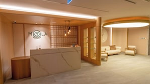 Een receptie met een marmeren balie, houten lambrisering en een zithoek met een bank en stoelen.