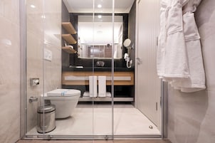 Un baño moderno con cabina de ducha de vidrio, inodoro y tocador con espejo y toallero.