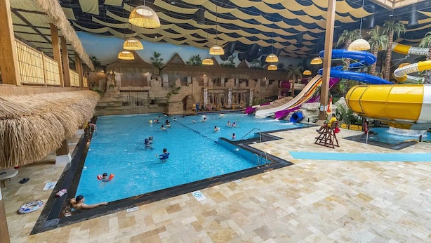 Een binnenzwembad met een waterglijbaan en een badmeesterstand.