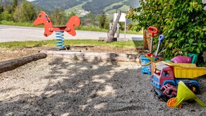 Un parque infantil con un columpio con forma de caballo, un camión de juguete y una pala.