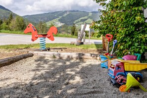 A playground with a horse-shaped swing, a toy truck, and a shovel.