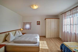 A bedroom with a bed, a wardrobe, and a window with curtains.