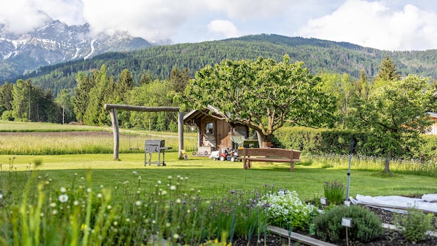 A rustic cabin with a wooden porch, surrounded by a well-maintained garden and a view of mountains. - Apartment '2' with Mountain View, Shared Garden and Wi-Fi (Oberolang)