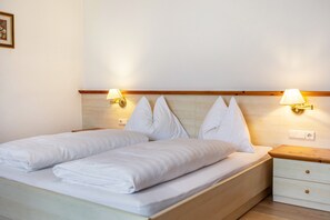 Ein Doppelbett mit weißen Bettwäsche, zwei Nachttische mit Lampen und ein Holzkopfstück.