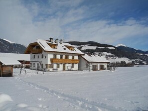 A snow-covered building with a balcony, surrounded by mountains and a clear sky. - Apartment '2' with Mountain View, Shared Garden and Wi-Fi (Oberolang)