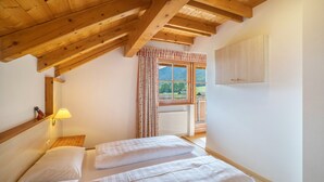 Une chambre avec un plafond en bois, une fenêtre avec des rideaux, une lampe de chevet et une vue sur l’extérieur.