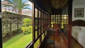 Una habitación con un ventanal grande, una cama, una silla y una mesita.