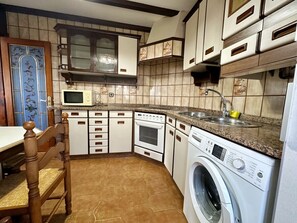 Una cocina compacta con lavadora, microondas y pileta.