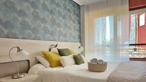 A bedroom with a bed, bedside tables, a lamp, and a basket with towels.