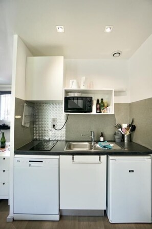 A compact kitchen with a microwave, sink, and two dishwashers.