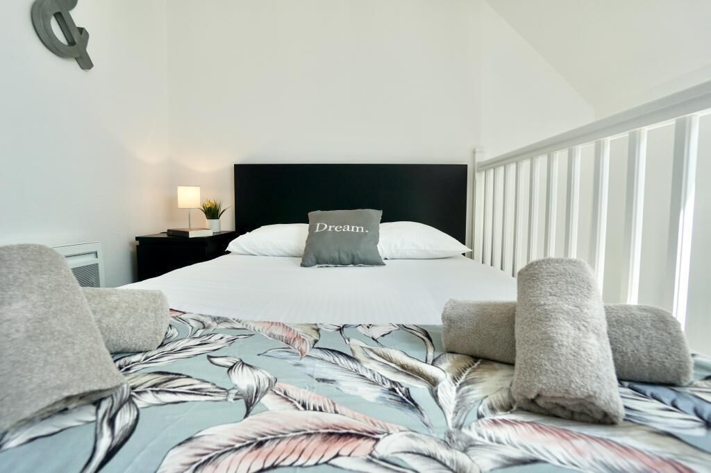 Una habitación de hotel con cama, mesita de noche, lámpara y vista al exterior.