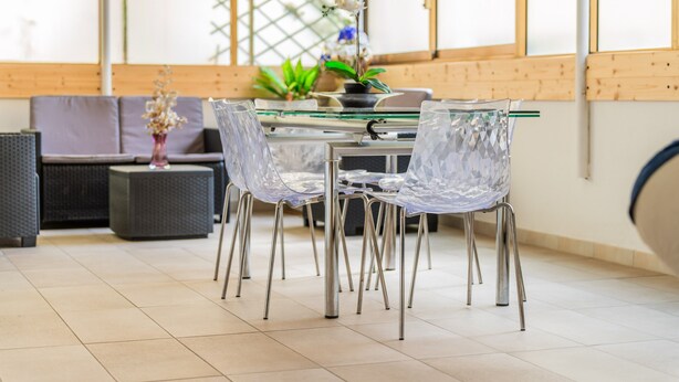 A modern dining area with a glass table, clear chairs, and a potted plant. - 'Dante House' Apartment in the centre ideal for groups (Cagliari)
