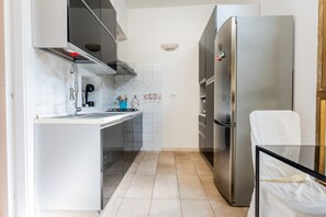 A compact kitchen with a stainless steel refrigerator, a built-in oven, and a sink.