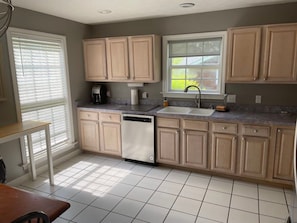 A kitchen with light wooden cabinets, a dishwasher, a sink, and a window with blinds. - Spacious Hendersonville Home – Sleeps 7, Prime Location! (Hendersonville)