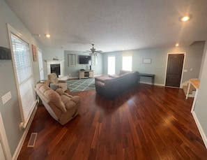 A spacious living room with hardwood flooring, a ceiling fan, and a fireplace. - Spacious Hendersonville Home – Sleeps 7, Prime Location! (Hendersonville)