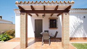 Eine Terrasse mit Tisch und Stühlen, einer Pergola und einer Backsteinmauer.