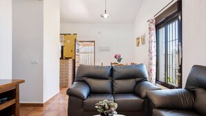 Ein Wohnzimmer mit einer Couch, einem Couchtisch mit einer Pflanze, einem Holznachttisch und einem Fenster mit Blick.