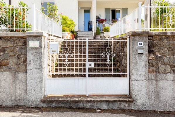 A gated entrance with a stone wall, a white gate, and a number '40' on the wall.